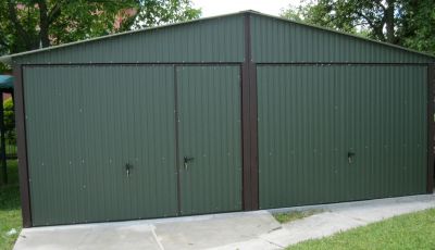 Ciemnozielony garaż z dwoma bramami, w tym jedna jest wyposażona w dodatkowe drzwi