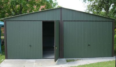 Zielony garaż na dwa stanowiska z otwartymi drzwiami w jednej z bram
