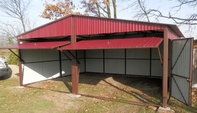 Czerwony garaż z uchylonymi bramami oraz dodatkowymi drzwiami